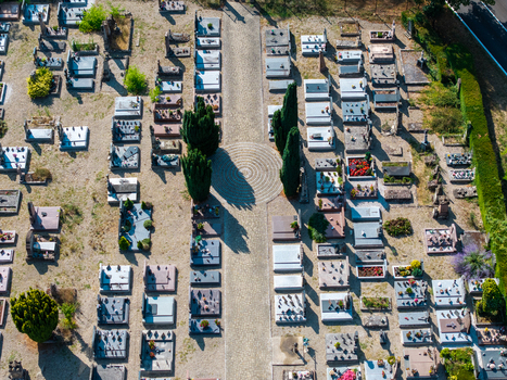Aerial view of the cemetery with rows of gravestones stone pathways and tall cypress trees casting long shadows on the ground in Neuf Brisach Grand Est France.
