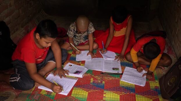 View of children studying on a mat in Bogura Bangladesh.