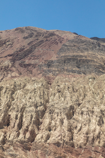 View of the rugged arid mountain slopes with distinct geological layers and rocky textures under a clear blue sky in Charasa Ladakh India.