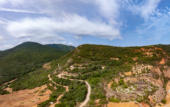 Aerial view of the historic iron mine area near Laghetto delle conche featuring winding dirt roads rugged hills and unique geological formations in Rio Marina Toscana Italy.
