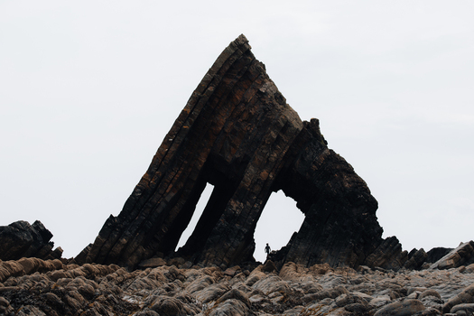 Westward Ho United Kingdom 23 July 2021 View of Blackchurch Rock with its distinctive jagged rock formation and a person standing beneath the arch on the rocky beach.