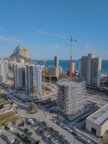 Aerial view of high rise residential buildings under construction with tall cranes near the iconic Penyal d Ifac rock formation in Calp Valencian Community Spain. Aerial view of high rise residential buildings under construction with tall cranes near the iconic Penyal d Ifac rock formation in Calp Valencian Community Spain.