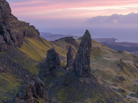 Aerial view of The Storr rock formation with jagged pinnacles and grassy slopes under a pink sunset sky Isle of Skye Scotland United Kingdom. Aerial view of The Storr rock formation with jagged pinnacles and grassy slopes under a pink sunset sky Isle of Skye Scotland United Kingdom.