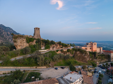 Aerial view of the historic Kruje Castle featuring the clock tower and Skanderbeg Museum surrounded by lush green hills and mountains in Kruje Durres County Albania.