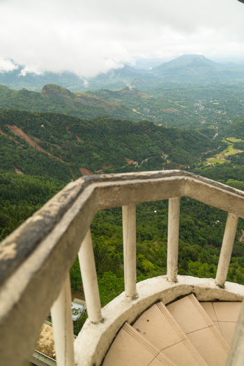 View of Ambuluwawa Tower overlooking lush green mountains and misty valleys under a cloudy sky Gampola Central Province Sri Lanka. View of Ambuluwawa Tower overlooking lush green mountains and misty valleys under a cloudy sky Gampola Central Province Sri Lanka.