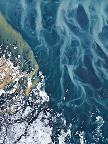 Aerial view of intricate glacial river patterns with turquoise sediment laden water flowing through snow covered volcanic terrain in Iceland. Aerial view of intricate glacial river patterns with turquoise sediment laden water flowing through snow covered volcanic terrain in Iceland.