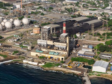Aerial view of the industrial power plant complex with large storage tanks smokestacks and coal piles situated along the coastline in Bajos de Haina San Cristobal Provinc Dominican Republic.
