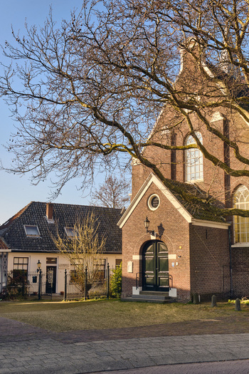 Wormerveer Netherlands 22 March 2026 View of renovated historic buildings along the Noordeinde with a brick church entrance and bare tree branches under a clear sky. Wormerveer Netherlands 22 March 2026 View of renovated historic buildings along the Noordeinde with a brick church entrance and bare tree branches under a clear sky.