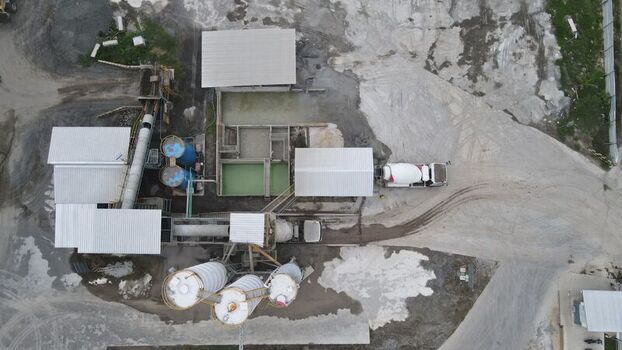 Aerial view of the concrete batching plant at the Dhoho International Airport construction site with industrial silos and a cement mixer truck in Kecamatan Grogol Jawa Timur Indonesia. Aerial view of the concrete batching plant at the Dhoho International Airport construction site with industrial silos and a cement mixer truck in Kecamatan Grogol Jawa Timur Indonesia.