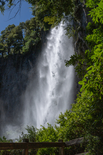 View of Cascada El Saltillo a powerful waterfall cascading down a rocky cliff face surrounded by lush green forest in Huiliches Department Neuquen Province Argentina. View of Cascada El Saltillo a powerful waterfall cascading down a rocky cliff face surrounded by lush green forest in Huiliches Department Neuquen Province Argentina.