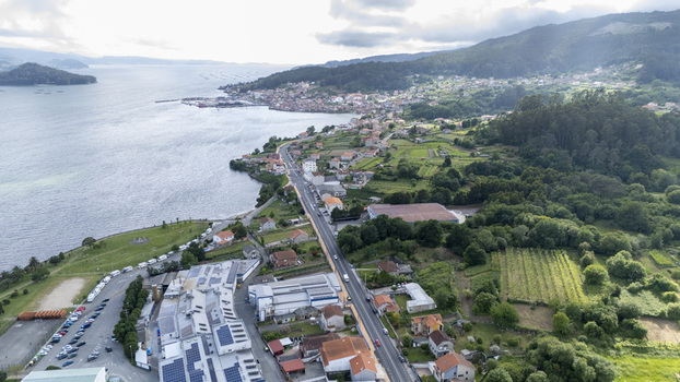 Aerial view of the coastal village featuring residential houses and a winding road along the bay surrounded by lush green hills Casalvito Pontevedra Spain. Aerial view of the coastal village featuring residential houses and a winding road along the bay surrounded by lush green hills Casalvito Pontevedra Spain.