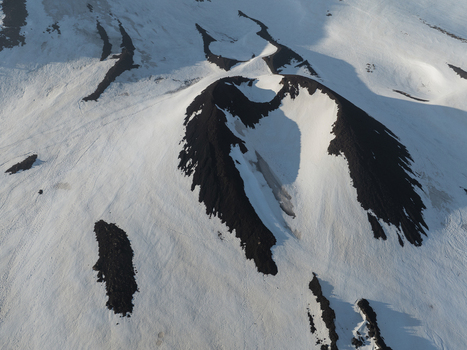 Aerial view of the snow covered volcanic craters on the south side of Mount Etna with dark volcanic rock contrasting against the white snow in Nicolosi Sicilia Italy. Aerial view of the snow covered volcanic craters on the south side of Mount Etna with dark volcanic rock contrasting against the white snow in Nicolosi Sicilia Italy.