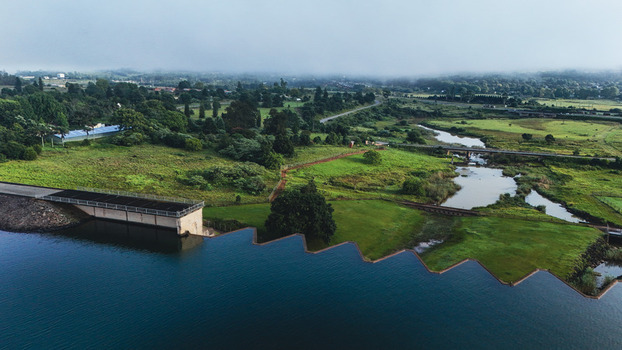 Aerial view of Midmar Dam featuring its unique zigzag spillway wall surrounded by lush green fields and misty hills in Howick KwaZulu Natal South Africa. Aerial view of Midmar Dam featuring its unique zigzag spillway wall surrounded by lush green fields and misty hills in Howick KwaZulu Natal South Africa.