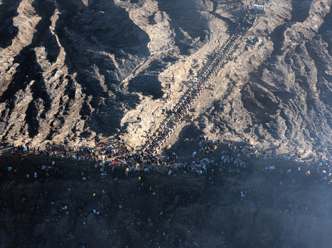 Aerial view of Mount Bromo crater rim with a large crowd of tourists walking along the narrow path on the rugged volcanic landscape in Kecamatan Sukapura Jawa Timur Indonesia.