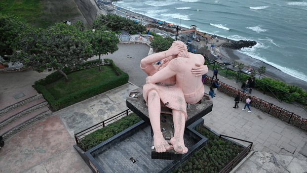 Aerial view of the El Beso sculpture in Love Park surrounded by lush greenery and stone walkways overlooking the Pacific Ocean coastline in Miraflores Provincia de Lima Peru.