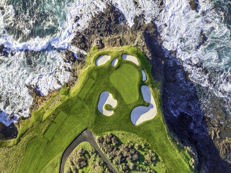 Aerial view of the 7th hole at Pebble Beach Golf Links featuring a green surrounded by sand bunkers and rugged cliffs overlooking the Pacific Ocean Pebble Beach CA United States. Aerial view of the 7th hole at Pebble Beach Golf Links featuring a green surrounded by sand bunkers and rugged cliffs overlooking the Pacific Ocean Pebble Beach CA United States.