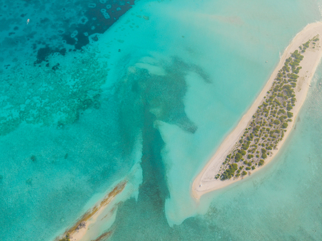 Aerial view of turquoise waters embrace the sandy Kan island with its crescent shape kissed by the sun Dhidhdhoo Thiladhunmathi Atoll Maldives.