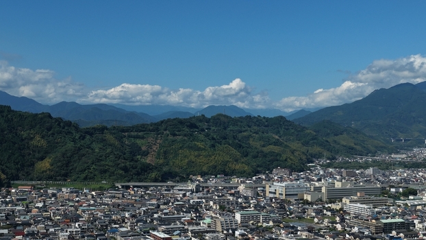 Aerial view of the cityscape of Shizuoka featuring dense residential areas modern buildings and lush green hills under a clear blue sky Shizuoka Shizuoka Japan.