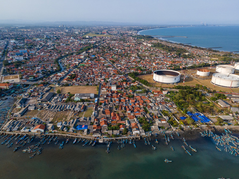 Aerial view of the coastal town of Cilacap Regency with harbor fishing boats residential area and industrial oil storage tanks in Cilacap Regency Central Java Indonesia. Aerial view of the coastal town of Cilacap Regency with harbor fishing boats residential area and industrial oil storage tanks in Cilacap Regency Central Java Indonesia.