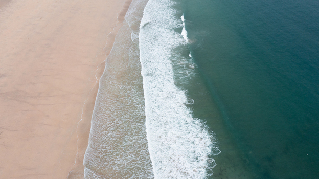 Aerial view of Harlyn Bay Beach with turquoise waves crashing onto the golden sand shore in Saint Merryn Cornwall United Kingdom.