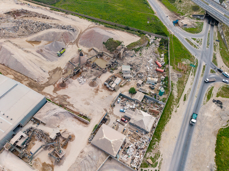 Aerial view of the Philippi industrial quarry site with piles of sand gravel and heavy machinery operating near a highway in Cape Town Western Cape South Africa.