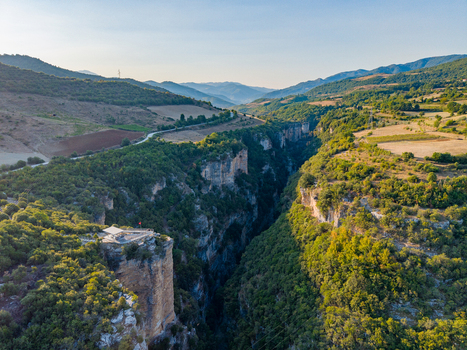 Aerial view of Osumi Canyon featuring steep limestone cliffs lush green vegetation and a winding river gorge in Dhores Berat County Albania.