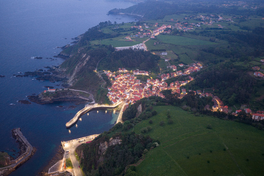Aerial view of the illuminated coastal village of Cudillero with its harbour and rugged cliffs at dusk in Cudillero Asturias Spain. Aerial view of the illuminated coastal village of Cudillero with its harbour and rugged cliffs at dusk in Cudillero Asturias Spain.