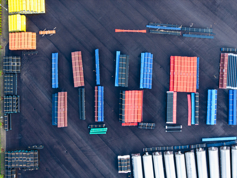 Aerial view of industrial storage yard featuring rows of colorful high efficiency polymer pipes and cylindrical containers arranged on asphalt in Jelgava Latvia. Aerial view of industrial storage yard featuring rows of colorful high efficiency polymer pipes and cylindrical containers arranged on asphalt in Jelgava Latvia.
