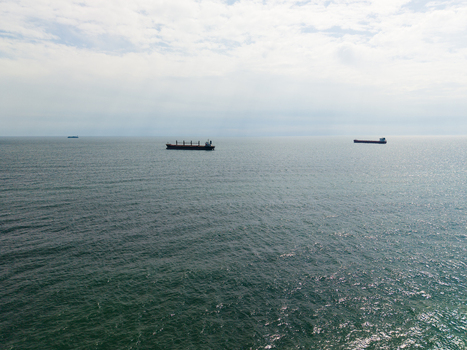 Aerial view of cargo ships anchored on the calm waters of the Black Sea under an overcast sky near Fichoza Beach Veteran in Varna Varna Bulgaria. Aerial view of cargo ships anchored on the calm waters of the Black Sea under an overcast sky near Fichoza Beach Veteran in Varna Varna Bulgaria.