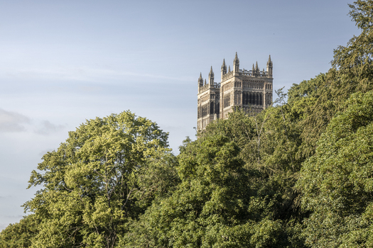 View of Durham Cathedral rising above the lush green trees under a clear blue sky in Durham England United Kingdom. View of Durham Cathedral rising above the lush green trees under a clear blue sky in Durham England United Kingdom.