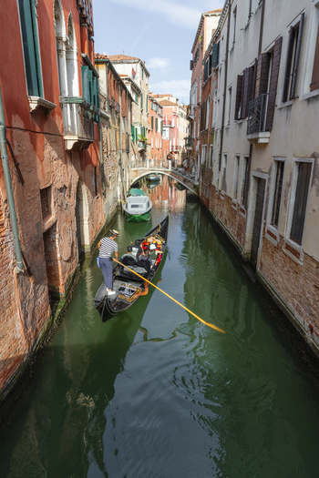 Venice Veneto Italy 21 September 2026 View of a gondolier rowing tourists through a narrow canal lined with historic buildings in Venice. Venice Veneto Italy 21 September 2026 View of a gondolier rowing tourists through a narrow canal lined with historic buildings in Venice.