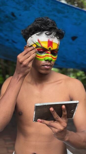 View of a Kathakali artist applying traditional face makeup in Kochi India. View of a Kathakali artist applying traditional face makeup in Kochi India.