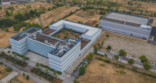 Alixan Auvergne Rhone Alpes France 25 July 2026 Aerial view of a modern technology campus with contemporary commercial buildings rooftop HVAC systems and surrounding dry landscape.