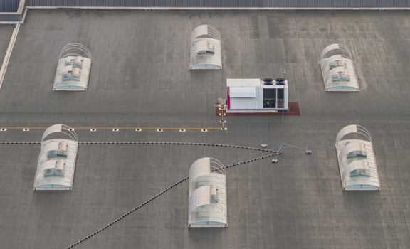 Aerial view of a modern industrial rooftop featuring arched skylights and HVAC cooling equipment in a clean geometric composition in Valence Auvergne Rhone Alpes France.