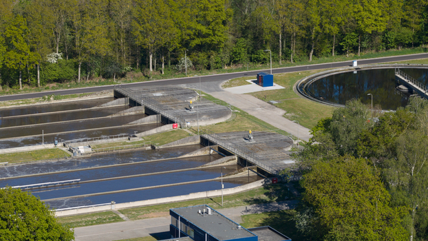 Aerial view of RWZI Echten wastewater treatment plant featuring circular tanks and rectangular basins surrounded by green trees in Hoogeveen Drenthe Netherlands. Aerial view of RWZI Echten wastewater treatment plant featuring circular tanks and rectangular basins surrounded by green trees in Hoogeveen Drenthe Netherlands.