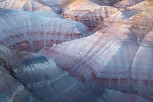 Aerial view of the mesmerizing and undulating landscape where bands of pastel blues purples and reds create a painterly tableau of natural artistry Hanksville Utah United States. Aerial view of the mesmerizing and undulating landscape where bands of pastel blues purples and reds create a painterly tableau of natural artistry Hanksville Utah United States.