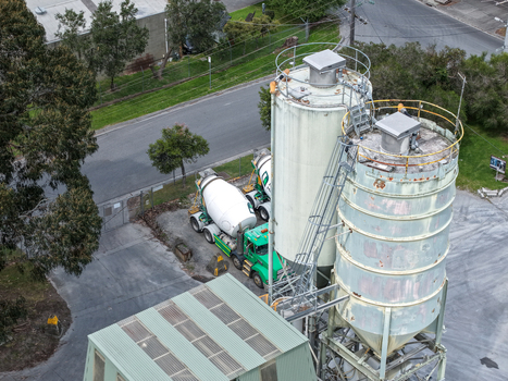 Melbourne VIC Australia 25 September 2026 Aerial view of industrial cement silos and a concrete mixer truck parked at a facility with surrounding trees and paved grounds.