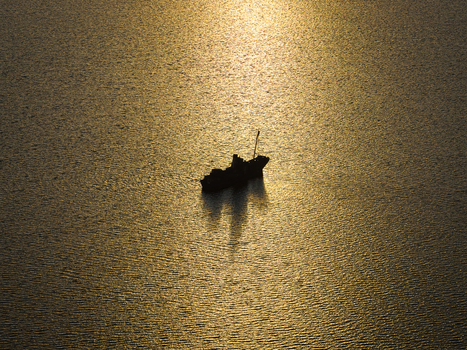 Aerial view of a ship silhouette floating on calm water during golden hour near Vancouver Peninsula Western Australia Australia. Aerial view of a ship silhouette floating on calm water during golden hour near Vancouver Peninsula Western Australia Australia.