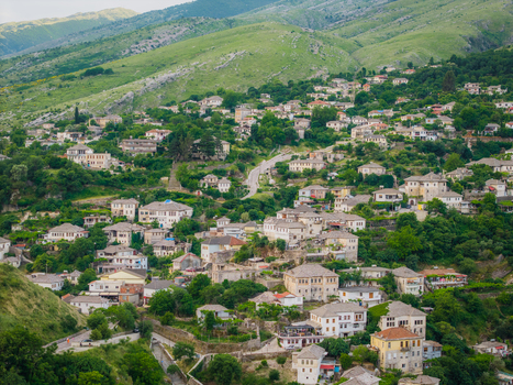 Aerial view of traditional stone houses with grey slate roofs on a lush green hillside in Gjirokaster Gjirokaster County Albania. Aerial view of traditional stone houses with grey slate roofs on a lush green hillside in Gjirokaster Gjirokaster County Albania.