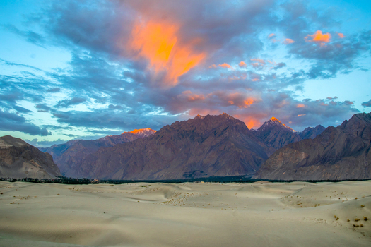 View of the Katpana Desert sand dunes and Karakoram mountains under a dramatic sunset sky in Skardu Gilgit Pakistan. View of the Katpana Desert sand dunes and Karakoram mountains under a dramatic sunset sky in Skardu Gilgit Pakistan.