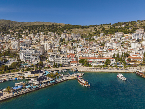Aerial view of the coastal city of Saranda with its bustling harbor boats docked at the marina dense urban architecture and scenic hills Saranda Vlore County Albania. Aerial view of the coastal city of Saranda with its bustling harbor boats docked at the marina dense urban architecture and scenic hills Saranda Vlore County Albania.