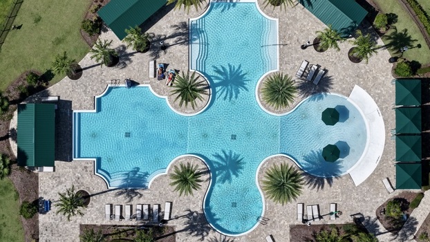 Aerial view of the swimming pool at Windward Ranch with turquoise water stone decking palm trees and green cabanas in St. Johns County Florida United States. Aerial view of the swimming pool at Windward Ranch with turquoise water stone decking palm trees and green cabanas in St. Johns County Florida United States.