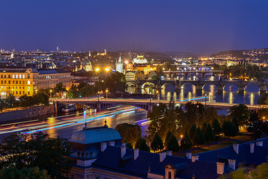 View of the illuminated Charles Bridge and Vltava River at night with historic architecture and light trails from boats in Prague Prague Czechia.