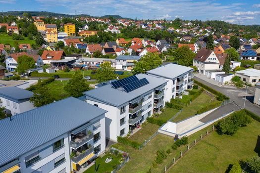 Aerial view of modern residential buildings with solar panels on rooftops and a suburban landscape under a clear blue sky Erlangen Bavaria Germany.
