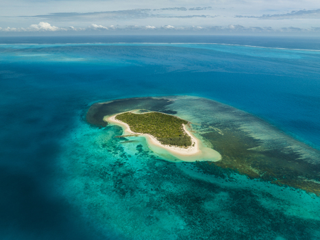 Aerial view of a lush green island surrounded by turquoise waters fringed with coral reefs and white sandy beaches Noumea New Caledonia. Aerial view of a lush green island surrounded by turquoise waters fringed with coral reefs and white sandy beaches Noumea New Caledonia.
