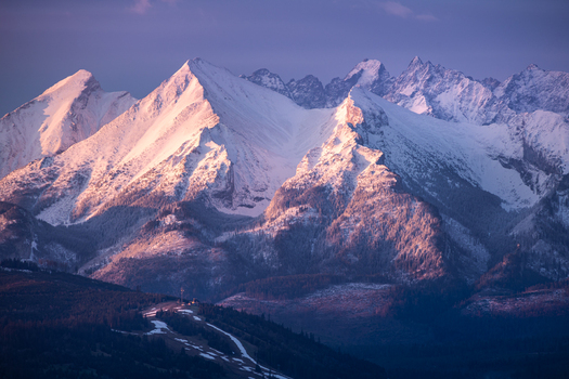 View of snow covered peaks of the Tatra Mountains illuminated by the warm light of sunset with forested slopes in the foreground Czarna Gora Lesser Poland Poland. View of snow covered peaks of the Tatra Mountains illuminated by the warm light of sunset with forested slopes in the foreground Czarna Gora Lesser Poland Poland.