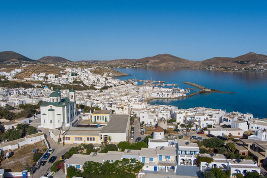 Parikia Greece 21 September 2026 Aerial view of the coastal town of Parikia on Paros featuring white washed buildings a church with a green dome a harbor and blue waters. Parikia Greece 21 September 2026 Aerial view of the coastal town of Parikia on Paros featuring white washed buildings a church with a green dome a harbor and blue waters.