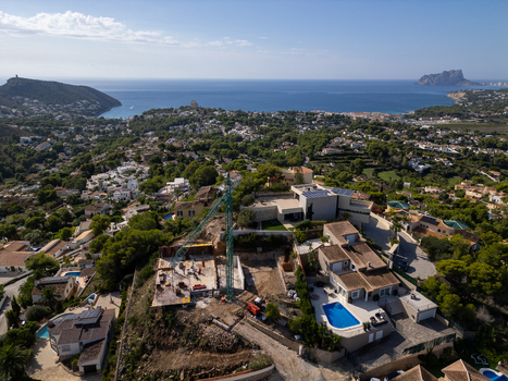 Aerial view of a construction site with a crane in a residential area overlooking the Mediterranean Sea in Moraira Valencian Community Spain.