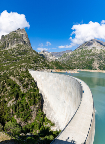 View of the massive concrete arch of the Emosson Dam holding back the turquoise reservoir water surrounded by steep rocky mountain slopes in Le Chatelard Valais Switzerland. View of the massive concrete arch of the Emosson Dam holding back the turquoise reservoir water surrounded by steep rocky mountain slopes in Le Chatelard Valais Switzerland.
