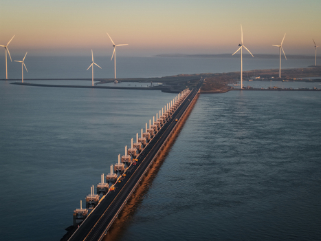 Aerial view of the Delta Projects Netherlands storm surge barrier with wind turbines and a road crossing the sea at sunset in Vrouwenpolder Zeeland Netherlands.